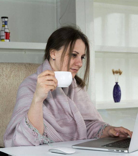 Someone writing at a laptop with a cup of coffee