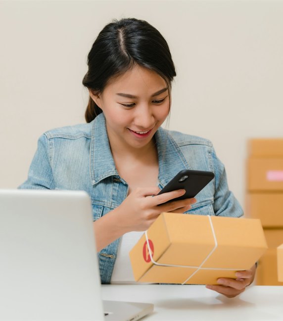A shop owner at a laptop surrounded by packed orders