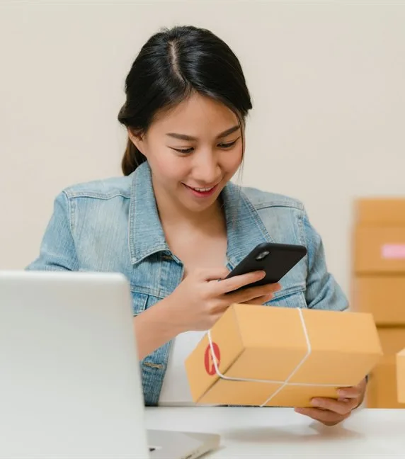 A shop owner at a laptop surrounded by packed orders